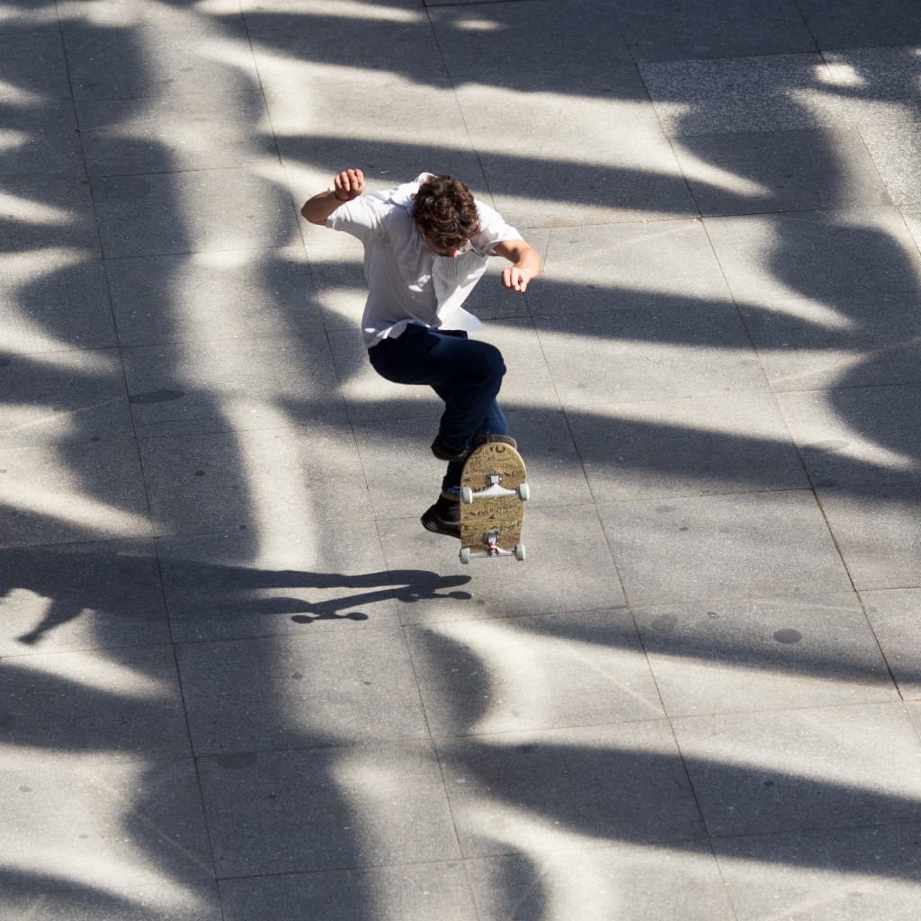 Skateboarder performing a kickflip on tiled pavement